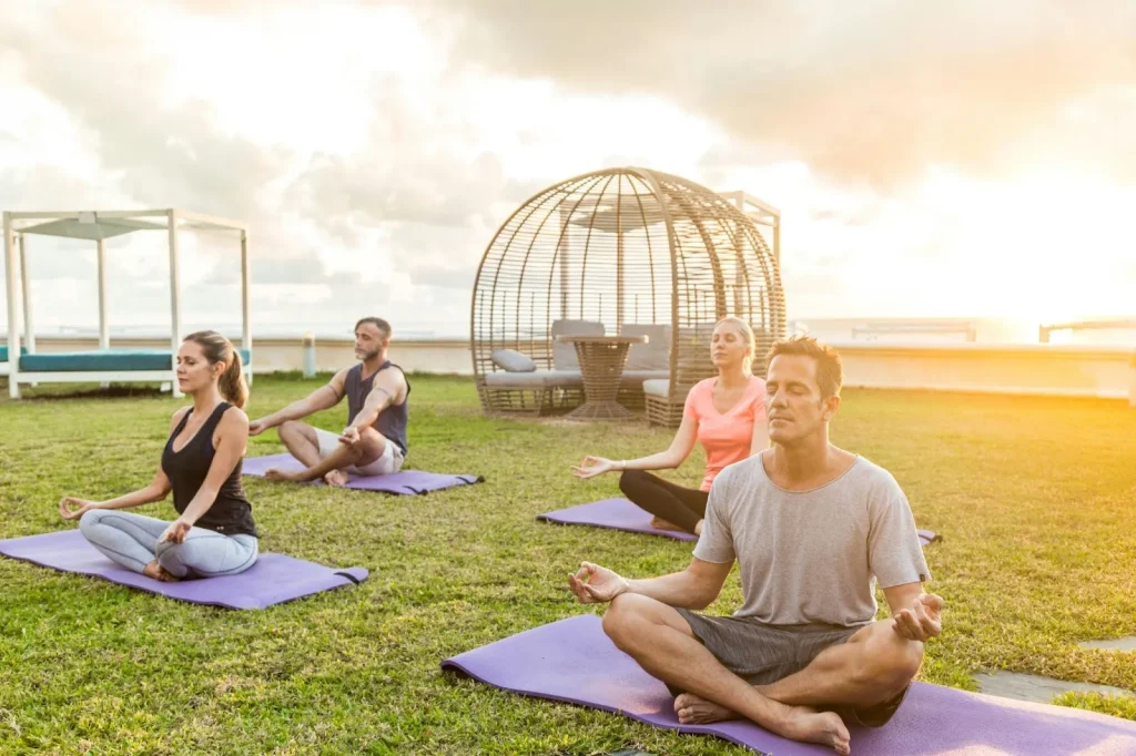 A group of four people meditating on their yoga mats outdoors in Koh Tao