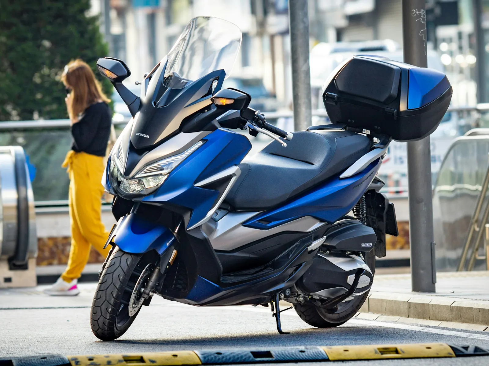 A blue and black Honda scooter parked along the road