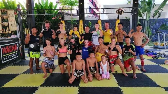 A group of students across all ages posing with a fist stance inside the King of Muay Thai Gym in Hua Hin