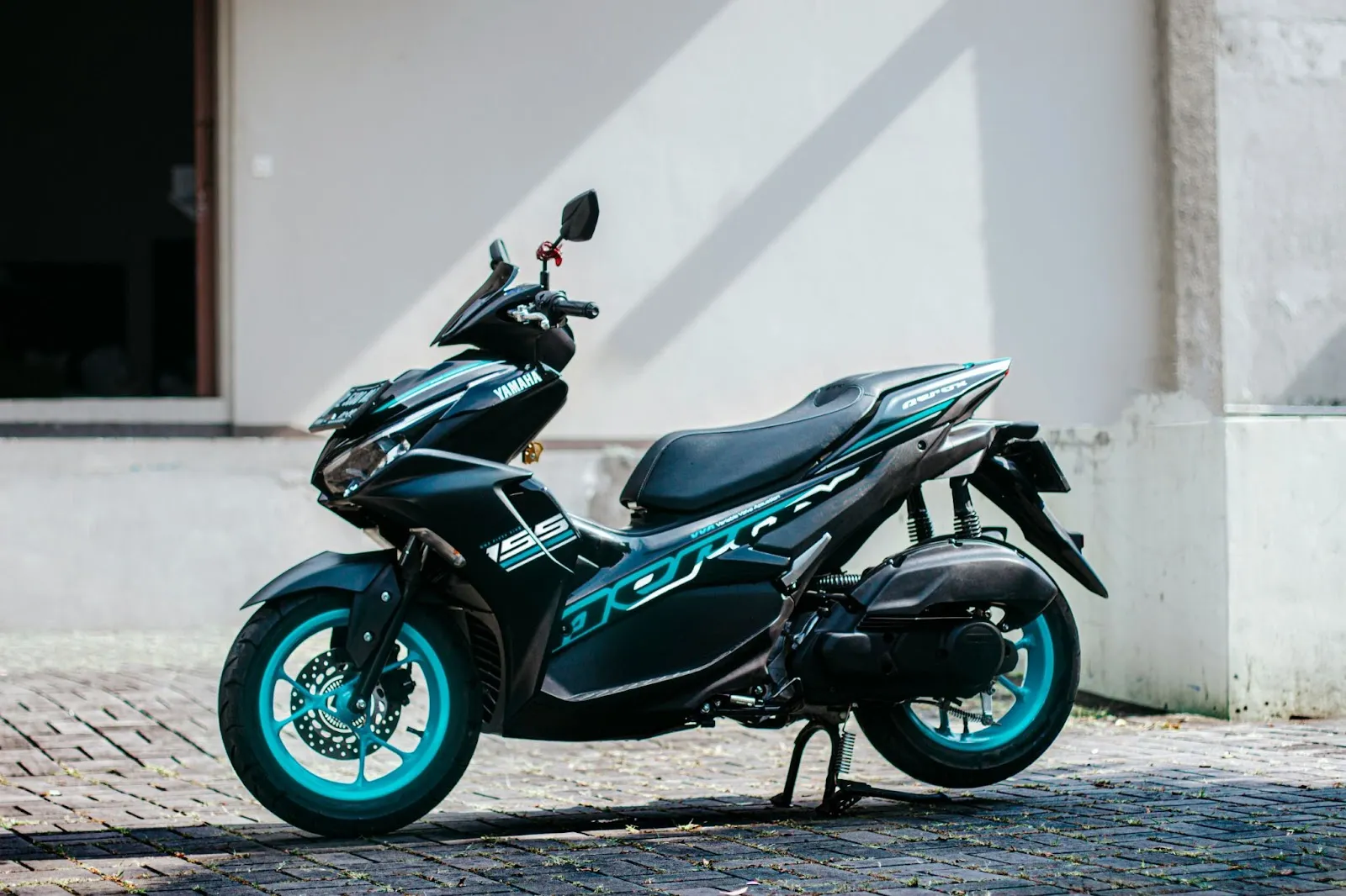 A black Yamaha Aerox motorbike with aqua blue accent