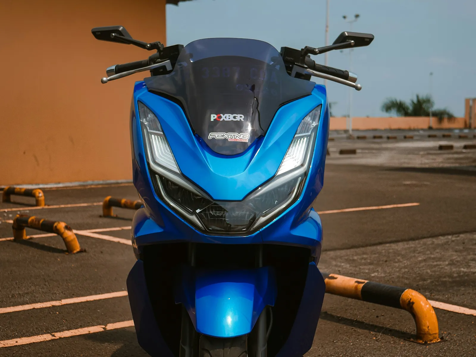 A blue Honda PCX motorbike parked on an empty parking lot