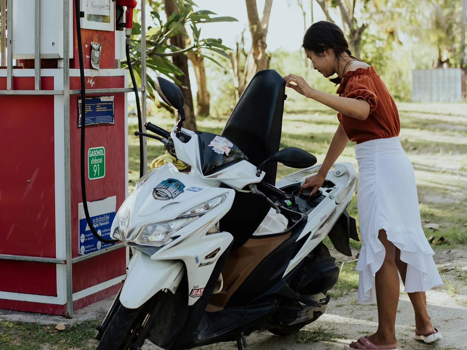 A woman filling up her Honda Click motorbike with gasoline

