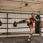 A woman in a high-kick stance inside the boxing ring