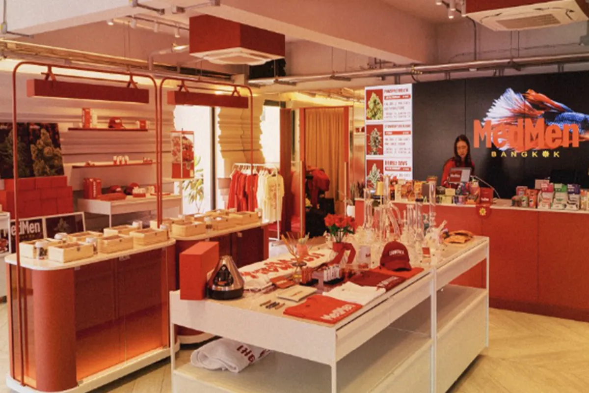 A view inside the red and white-themed store display of MedMen Bangkok, showcasing various cannabis products, accessories, and apparel