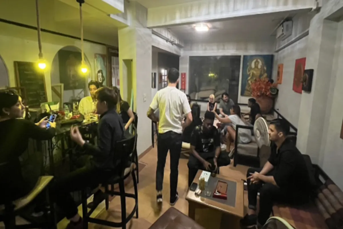 A peek at the casual gathering inside the Choo Choo Hemp’s lounge area. Some individuals are seated on chairs or sofas around a coffee table, while one person stands mid-motion, seemingly interacting with the group.
