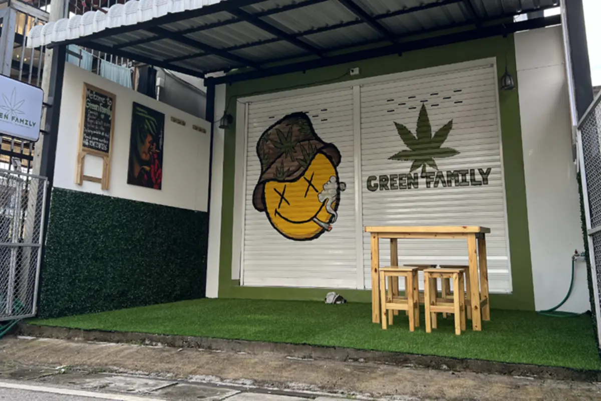 The storefront of the Green Family Cannabis Dispensary shows its roll-up door painted with a smiley face smoking weed.