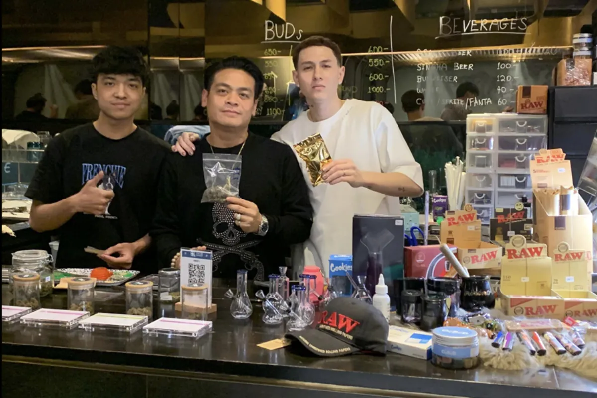 A group of three men highlight the various weed products offered at THC Thonglor Hemp Club in Bangkok