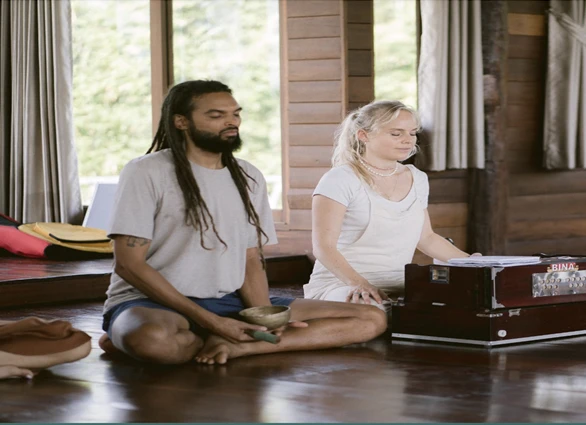 A man and a woman sitting still on the wooden floor inside Suan Sati Meditation Retreat in Chiang Mai