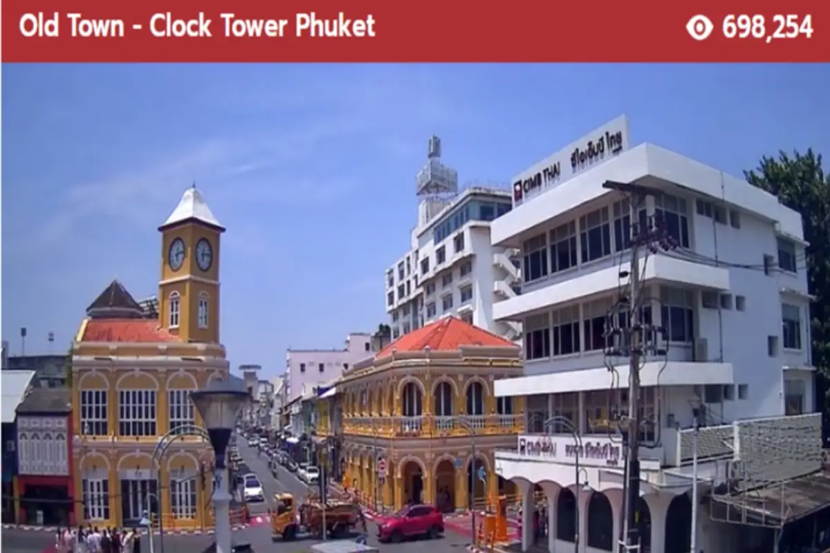 The image displays the vibrant and historic Old Town area of Phuket, featuring the distinctive Phuket Clock Tower with its yellow façade and white clock face.