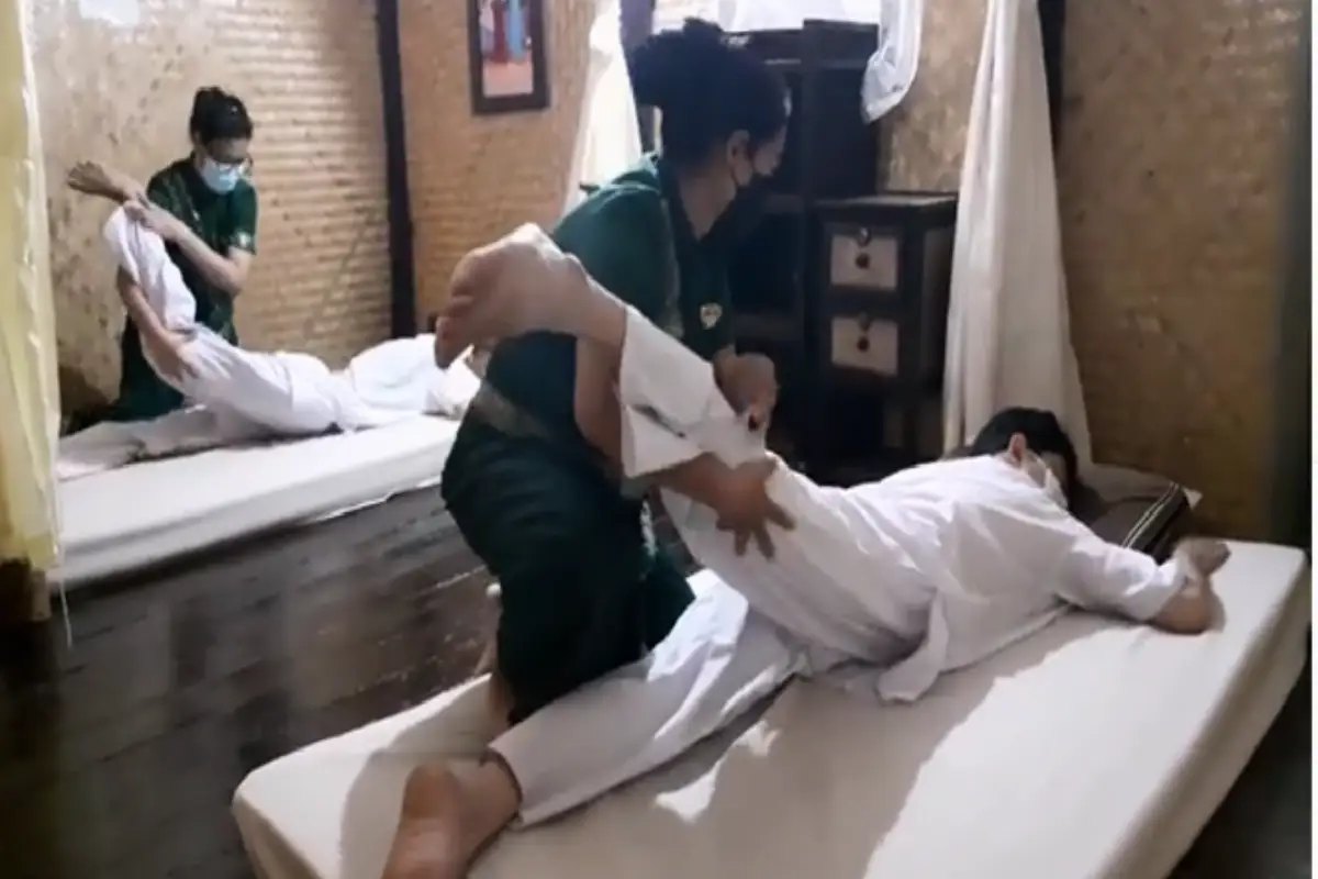 Two therapists are giving simultaneous body massages to two clients at Green Bamboo Massage in Chiang Mai