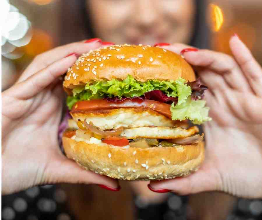 A closeup of a burger held by a woman’s hand