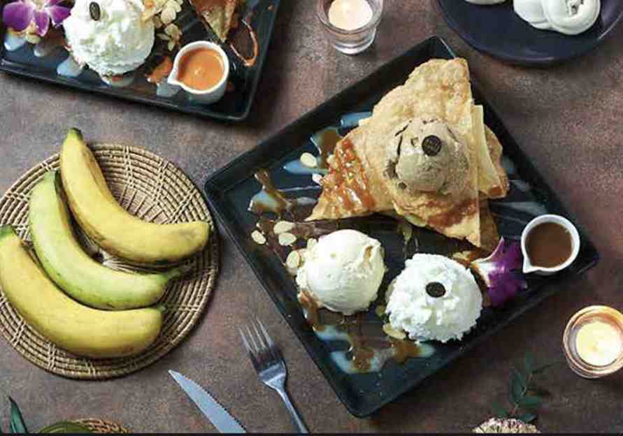 A flat lay of roti, homemade ice cream, and fresh banana served at White Flower Cafe in Bangkok