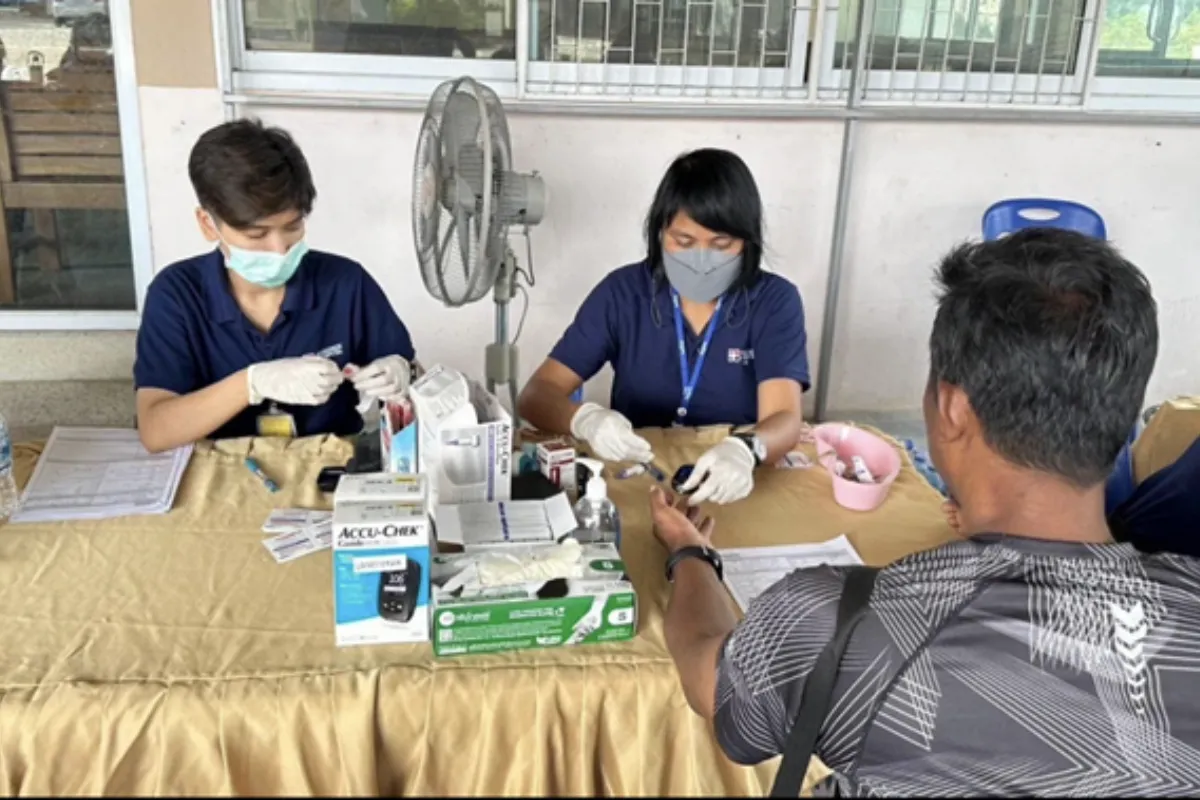 Two healthcare workers are extracting a blood sugar sample from a male patient at Bangkok Hospital Samui in Koh Samui.