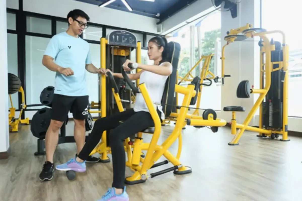 A male instructor is assisting a woman in using the gym equipment at Gorilla Gym in Chiang Rai