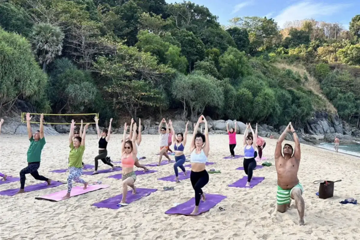 A group of people doing yoga at the beach shore of Mangosteen Ayurveda and Wellness Resort in Phuket.