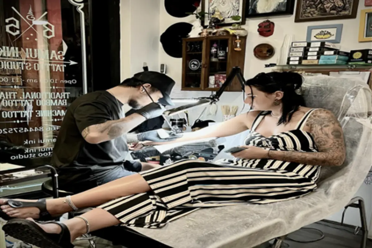 A female client is getting a hand-poked tattoo on her right forearm at Samui Ink Tattoo Studio in Koh Samui