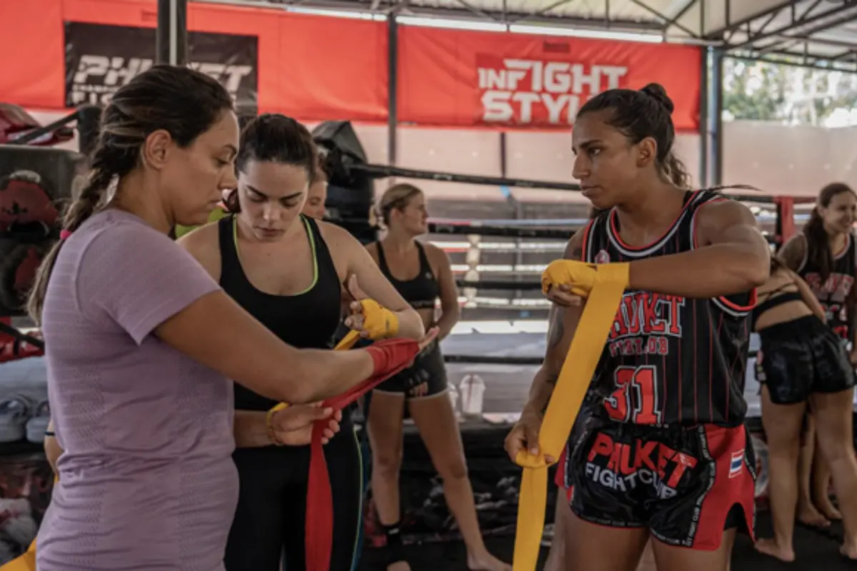 Two women being taught by their female instructor how to properly wrap their hands