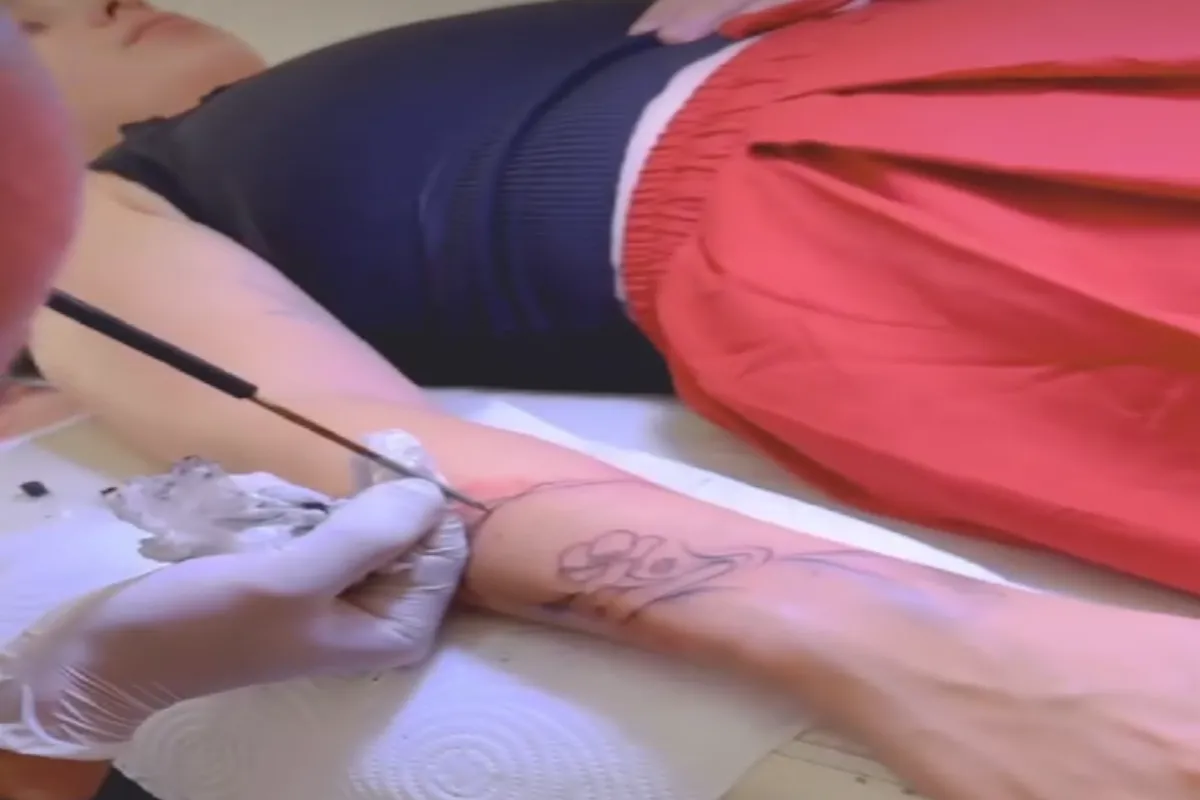 A woman is getting a free-hand tattoo using the bamboo stick technique by an artist at Zeroo Tattoo studio in Chiang Mai