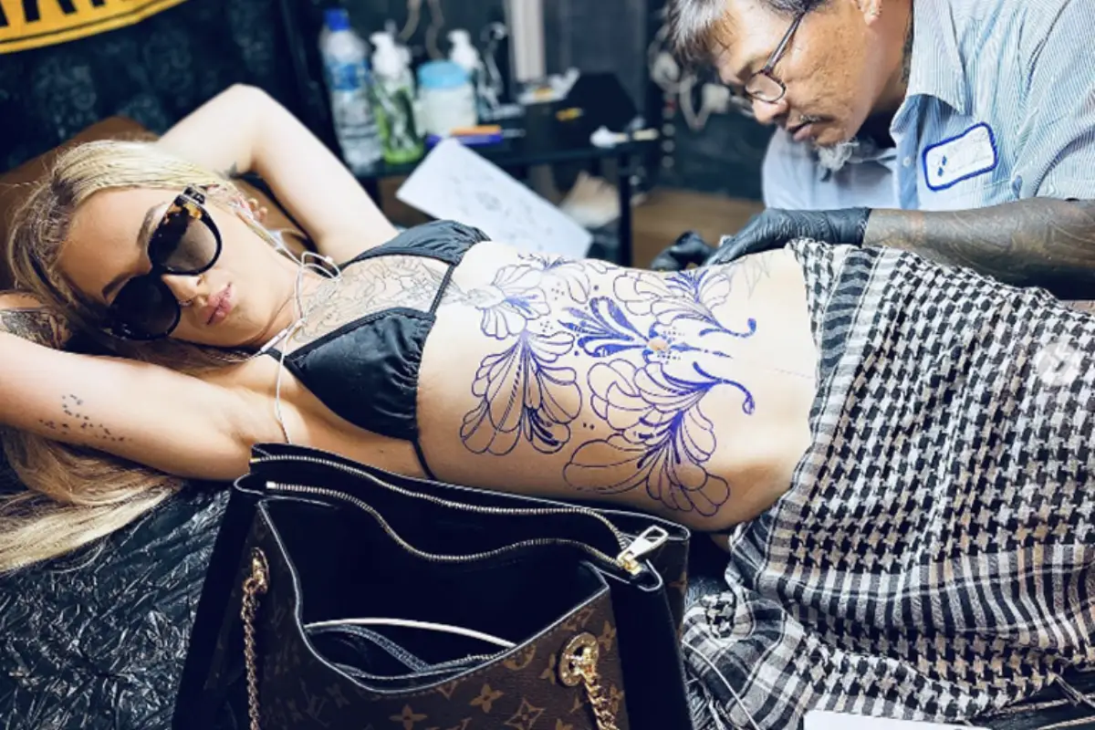 A woman is getting an extensive floral tattoo on her belly at Extreme Tattoo by Add in Koh Samui