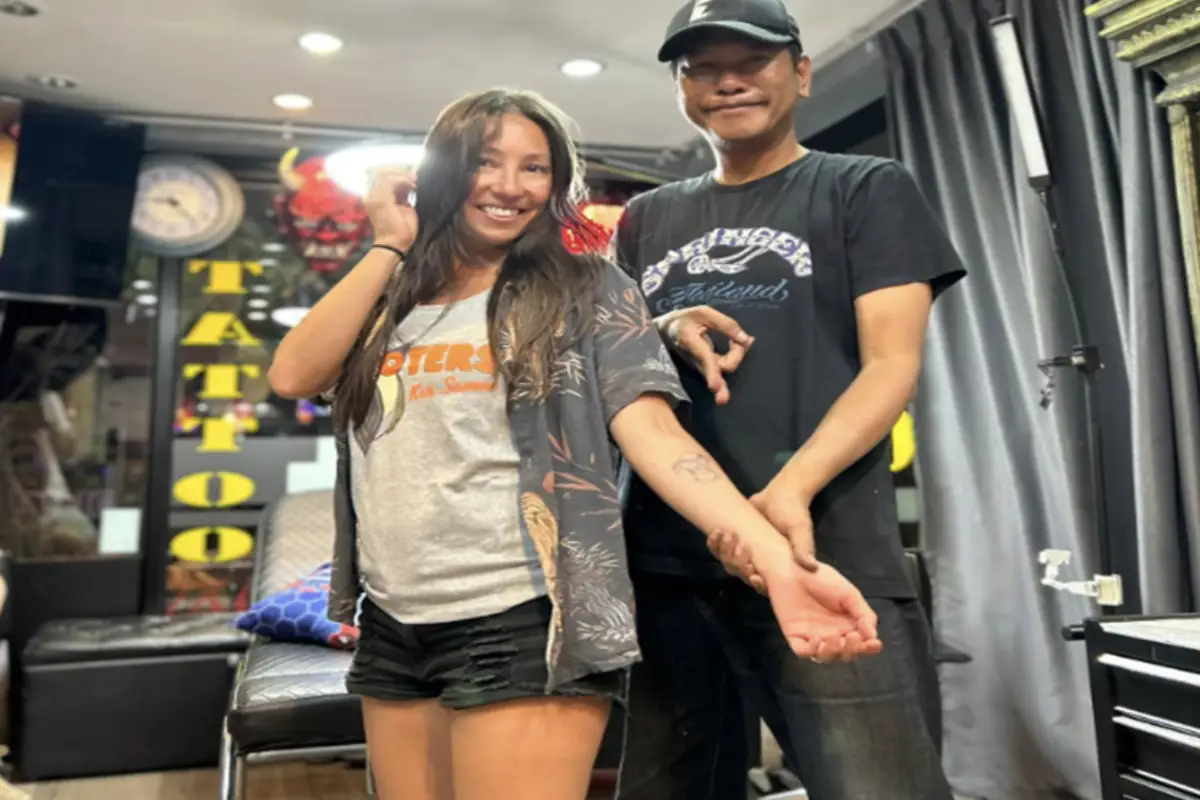 A tattoo artist at Power Bear Tattoo is showing off his female client’s bear tattoo on the forearm