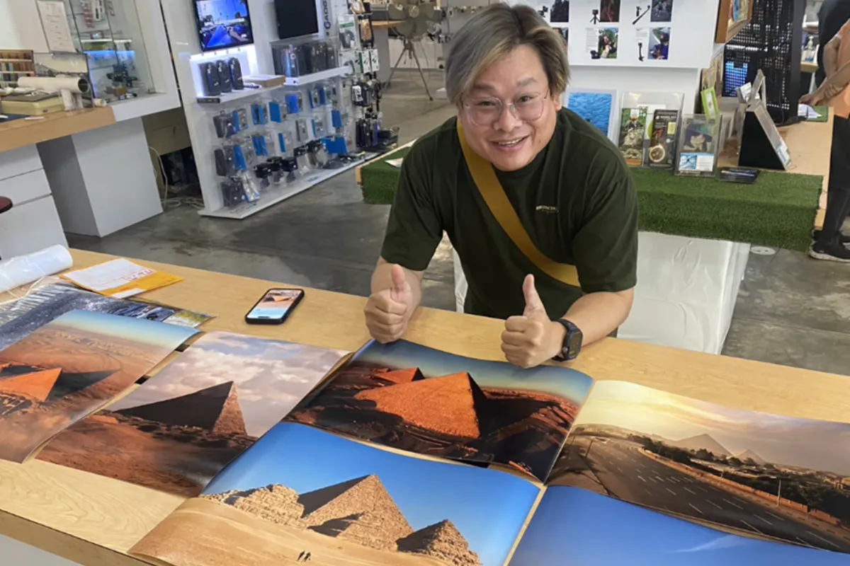 A photo of a man making a two-thumbs-up sign inside the Photo Bug Shop in Chaing Mai