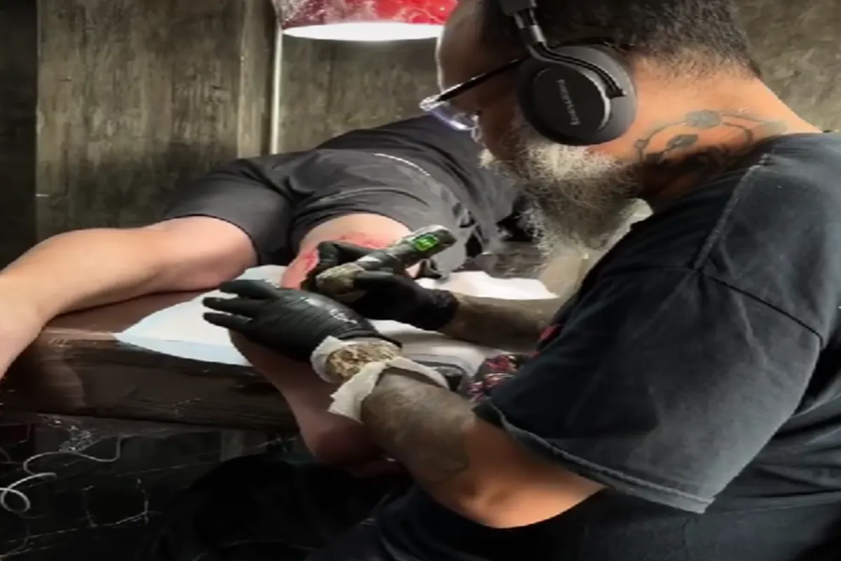 An artist is tattooing a man’s rear ankle at the Bloodline Tattoo Studio in Chiang Mai