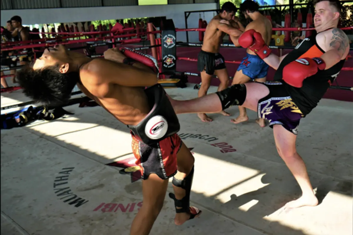 A Muay Thai student is practicing his kick with a trainer at Sinbi Muay Thai Training Camp.