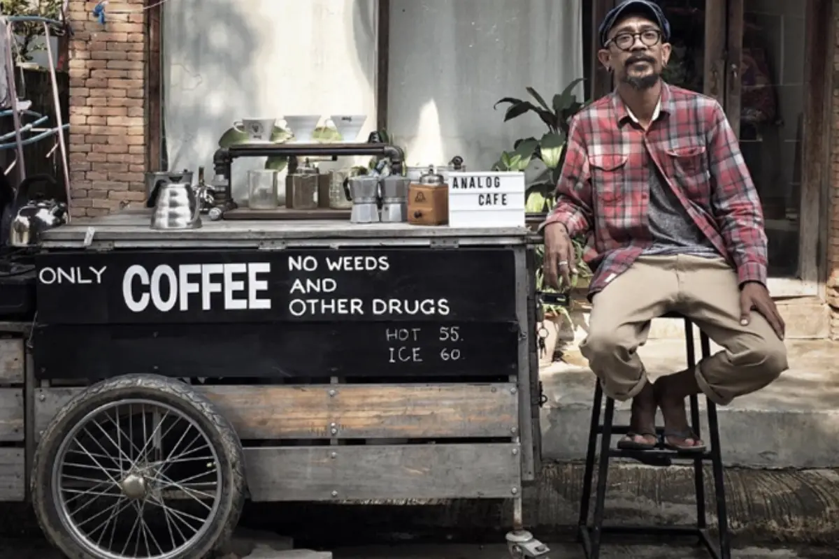 A man is sitting beside the rolling coffee shop of Analog Cafe in Pai