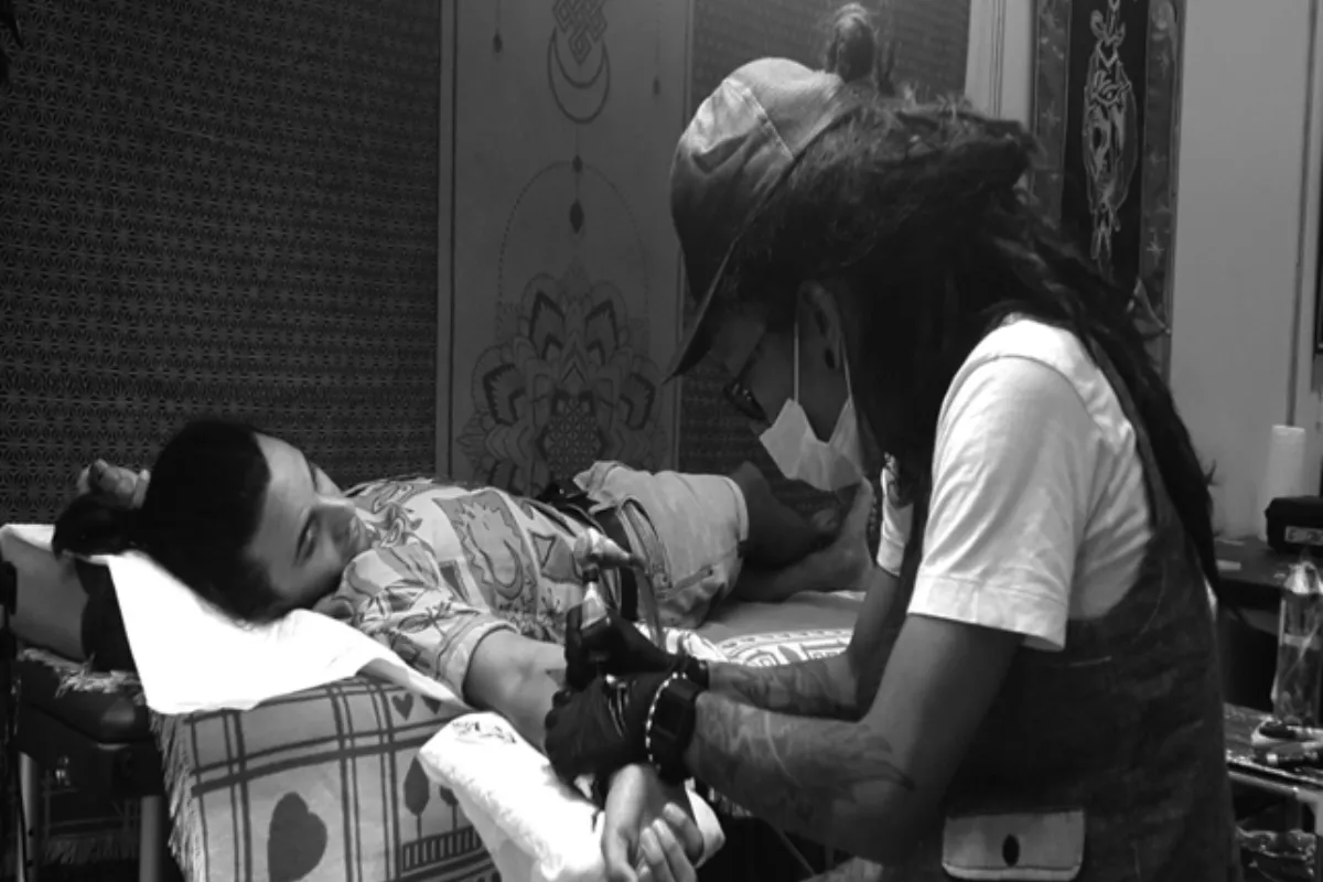 A black and white photo of Chiang Mai Skinart Studio artist Chris doing a tattoo on a man’s arm.