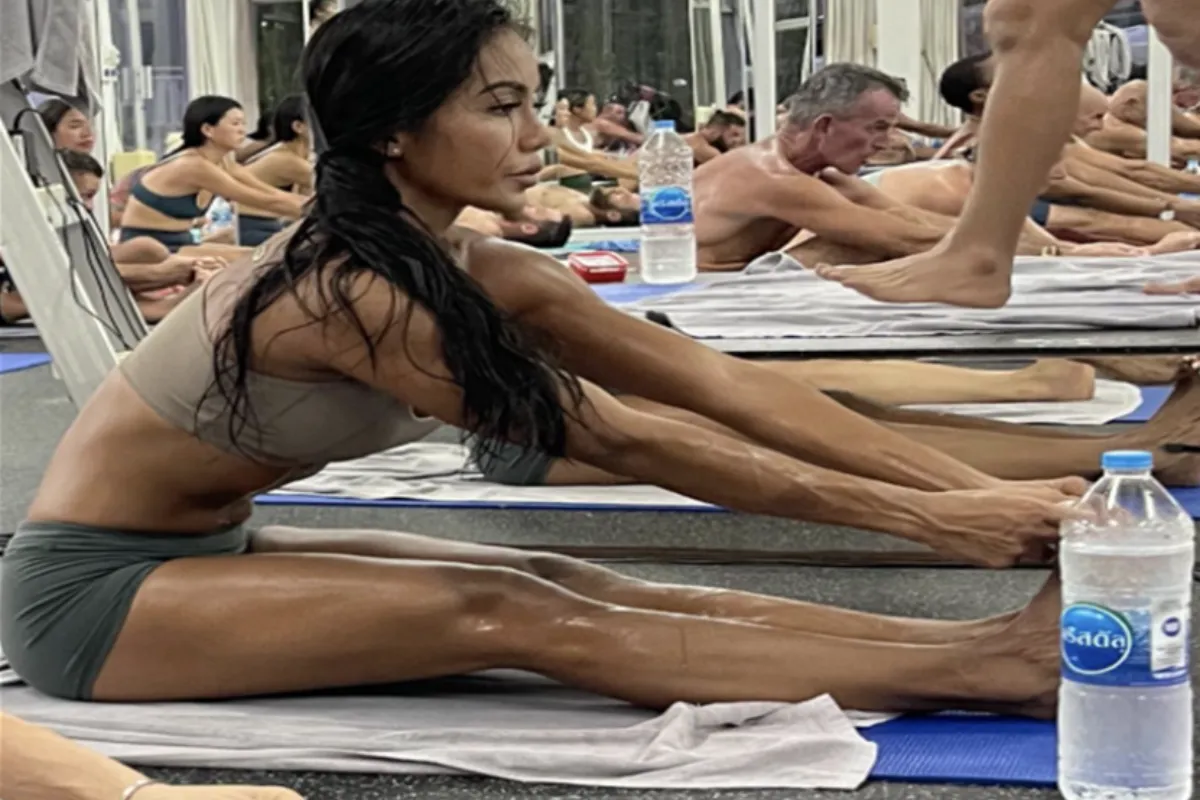 A woman is sitting on a yoga mat and sweating a lot during a hot yoga class at kata Hot Yoga in Phuket.