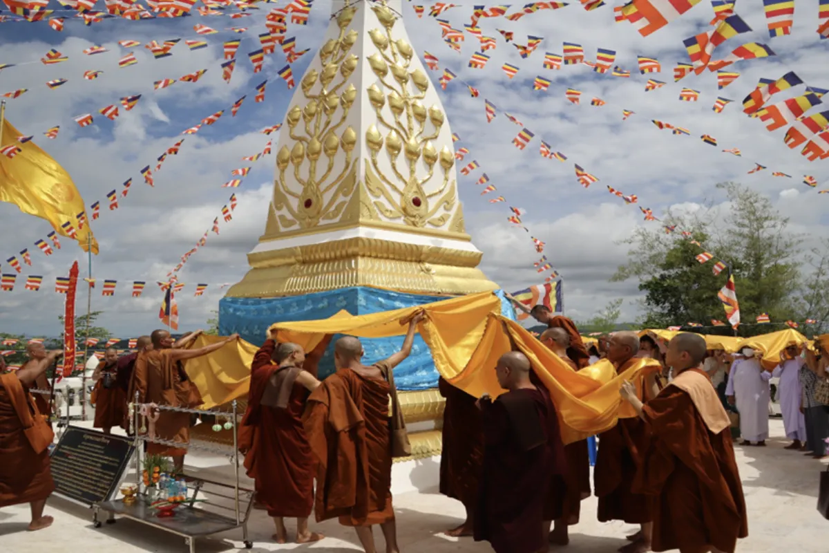A view of the monk carrying a yellow fabric in front of a shrine during a ceremony at Wat Khao Sanam Chai in Hua Hin