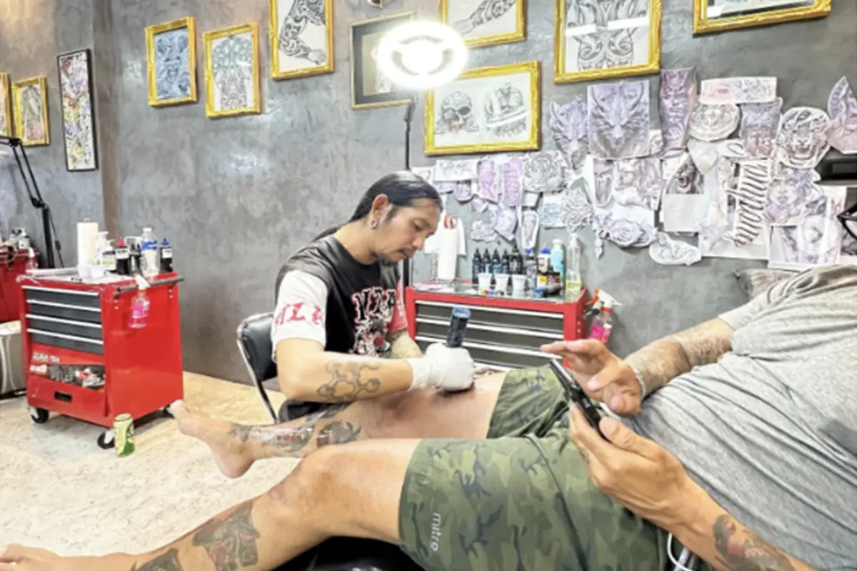 A man getting his tattoo done on his alright tight at Predator Tattoo Studio in Koh Samui