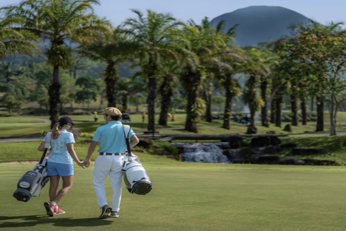 A male and a female golfer are carrying their golf bags while walking at Katathong Golf Resort and Spa in Phuket.