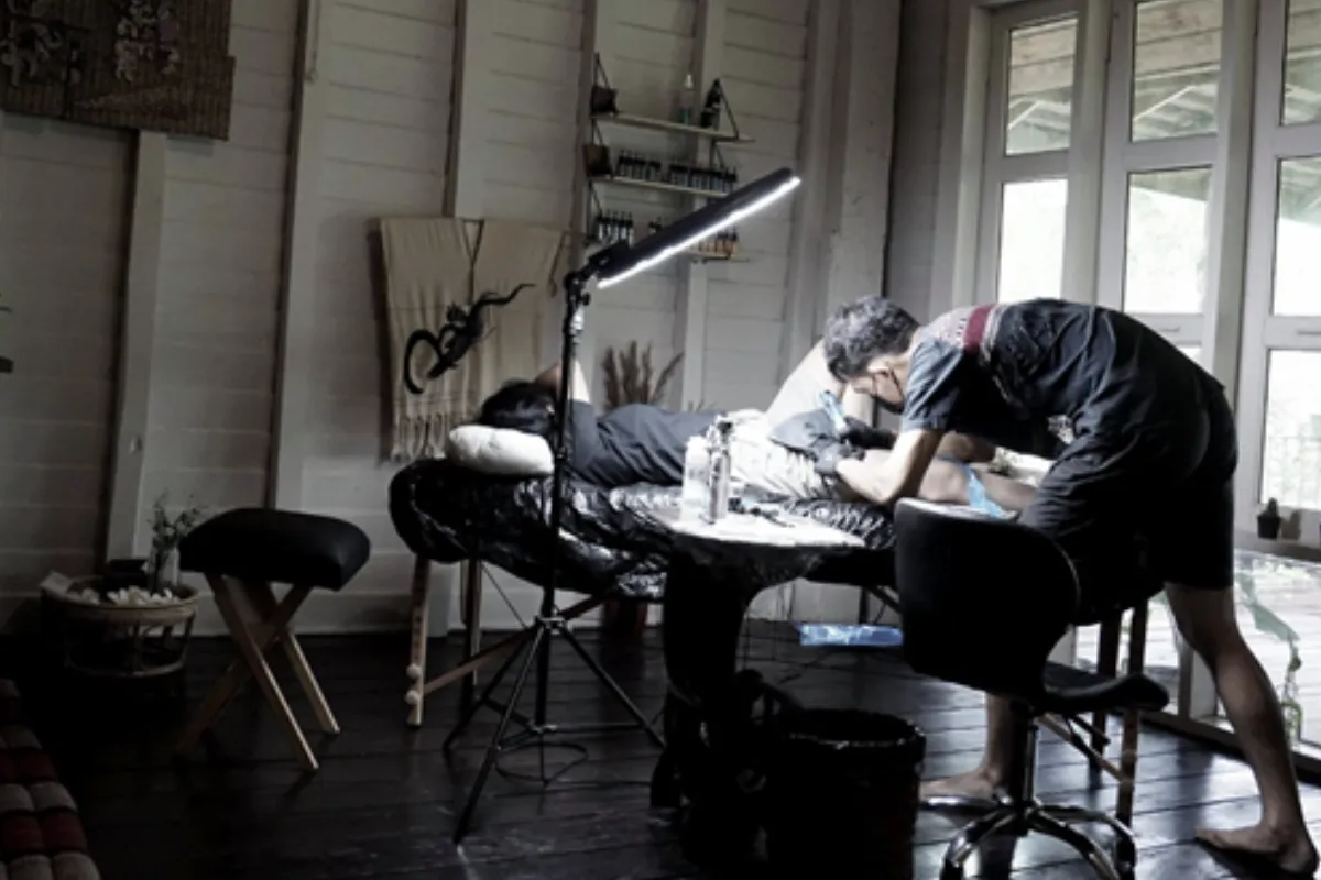 Baan Khagee Tattoo artist Nate is tattooing a woman’s leg inside his studio in Chiang Mai