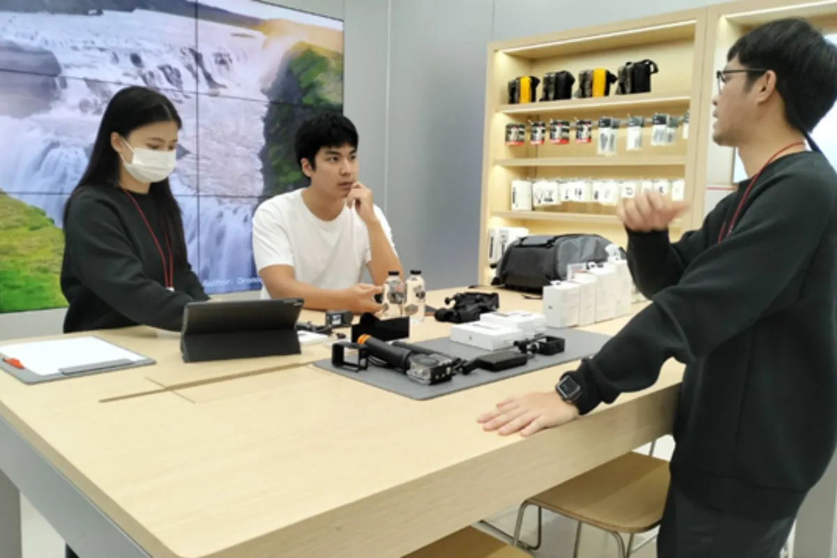Two sales person doing a demo on a DJI product to a male customer
