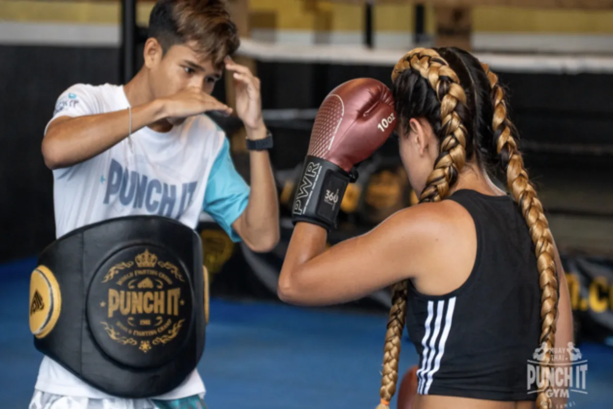 A male trainer is teaching a female trainee how to properly throw a punch at Punch It Gym in Koh Samui