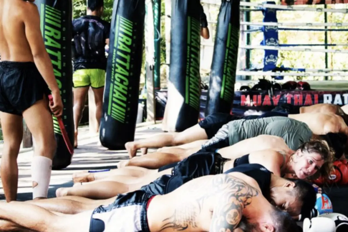 Muay Thai students practicing grappling techniques on the floor of Rattachai Muay Thai Gym.
