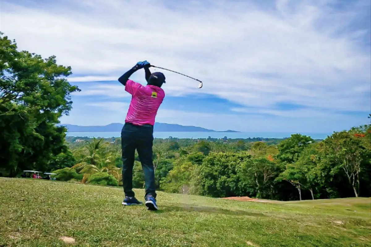 A man is swinging his golf club as he plays at the Santiburi Samui Country Club in Koh Samui
