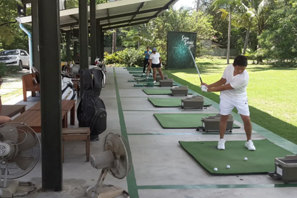 Three people lined up playing golf at Foothill Driving Range in Koh Samui