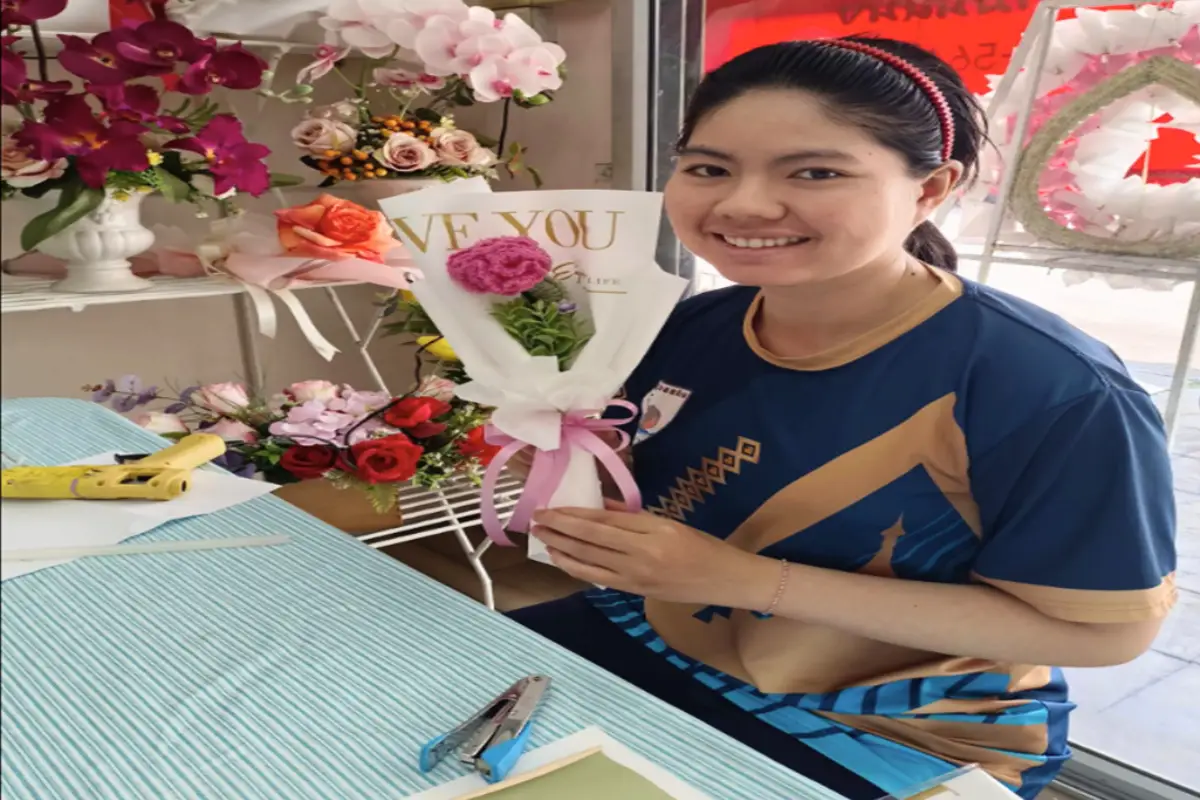 A woman is holding a small bouquet of of flower she created at Praemchompu Flower Shop in Chiang Mai