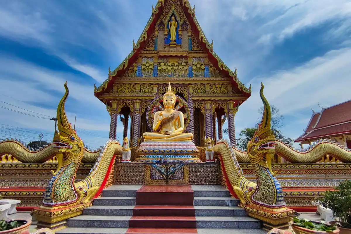 A view of a golden Buddha statue across a stair with dragon on the sides