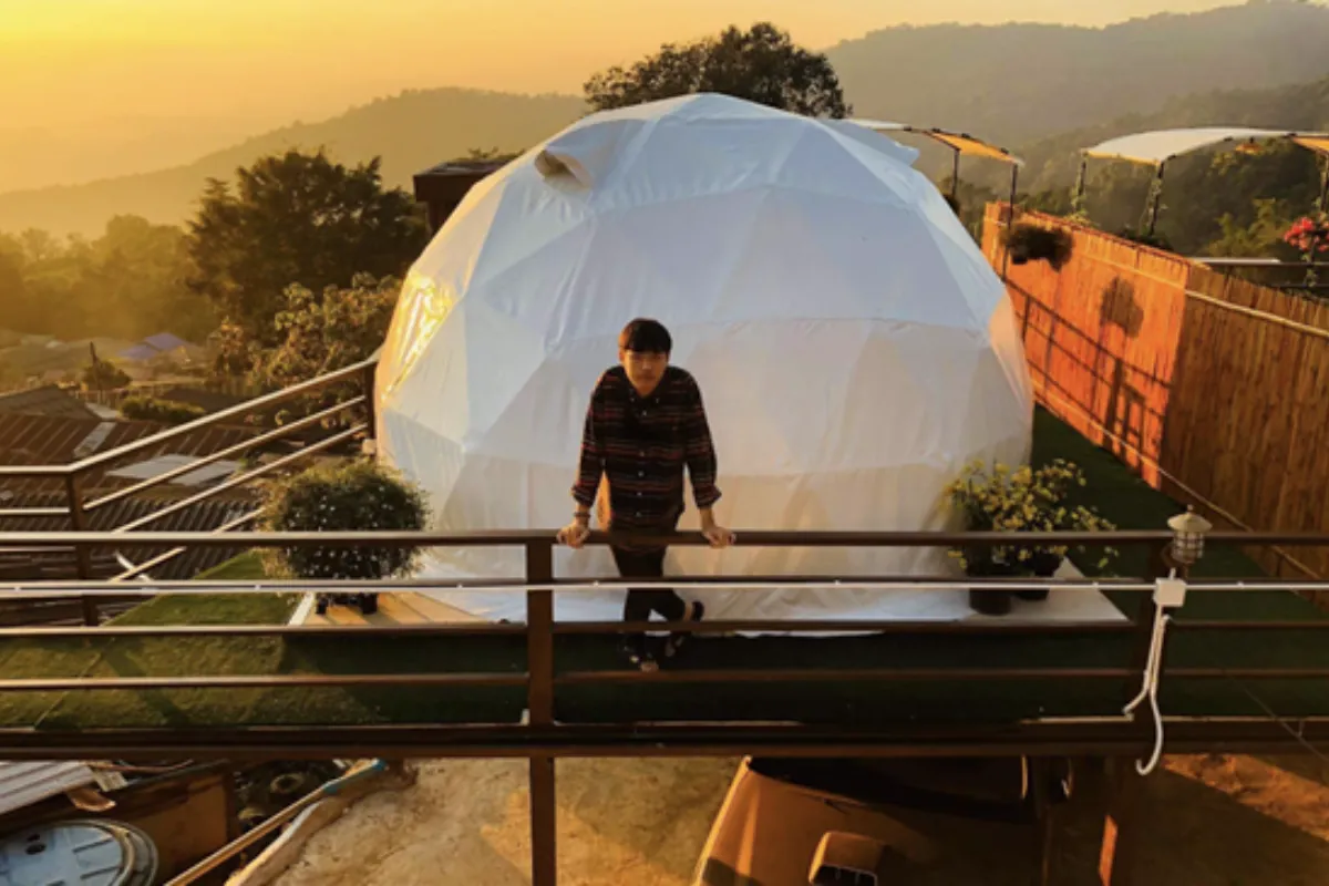 A man standing on a ledge in front of a dome tent at the Green Zone Homestay in Chiang Mai