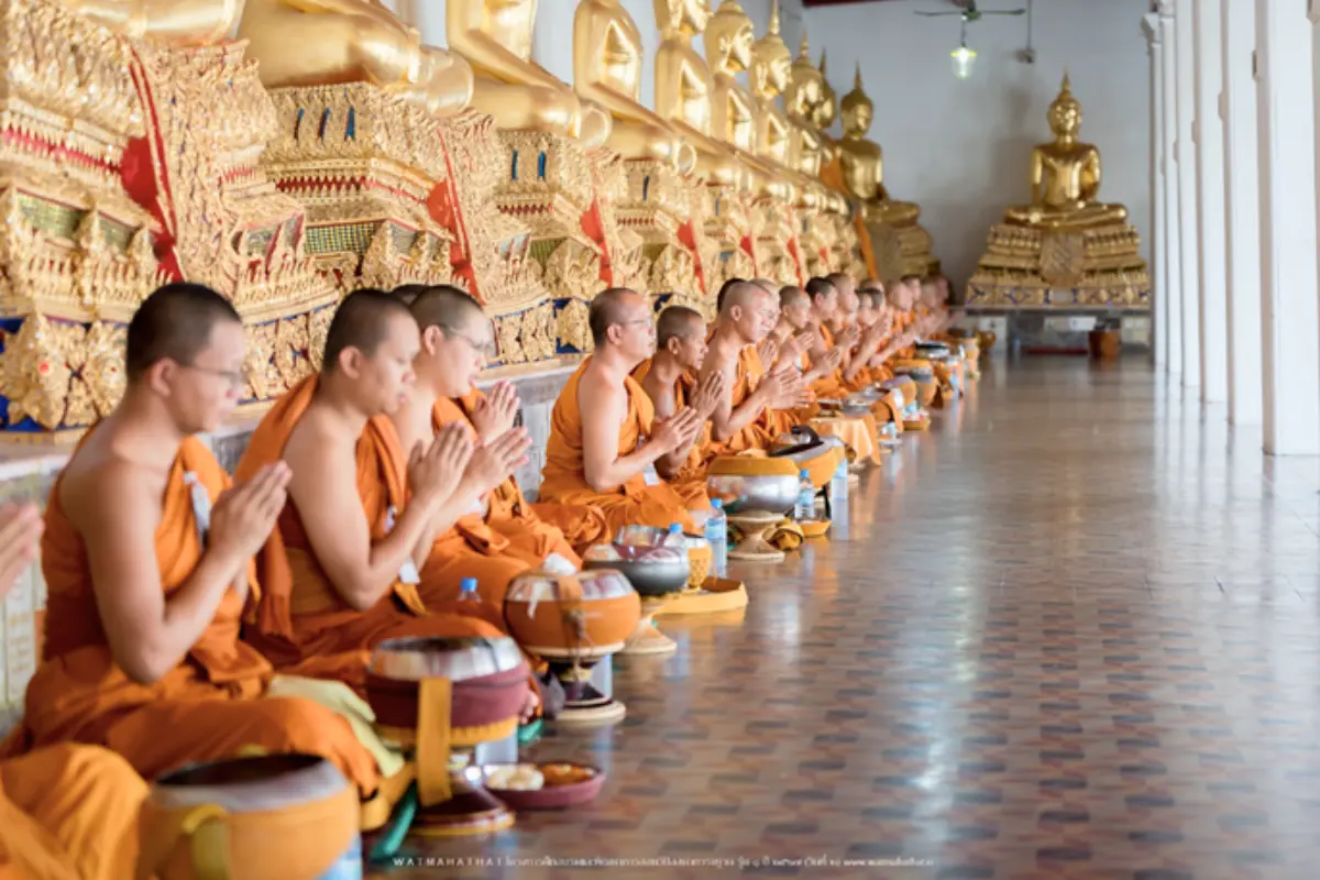 A row of monks sitting and chanting during a ceremony at the Wat Mahathat Yuwaratrangsarit in Bangkok