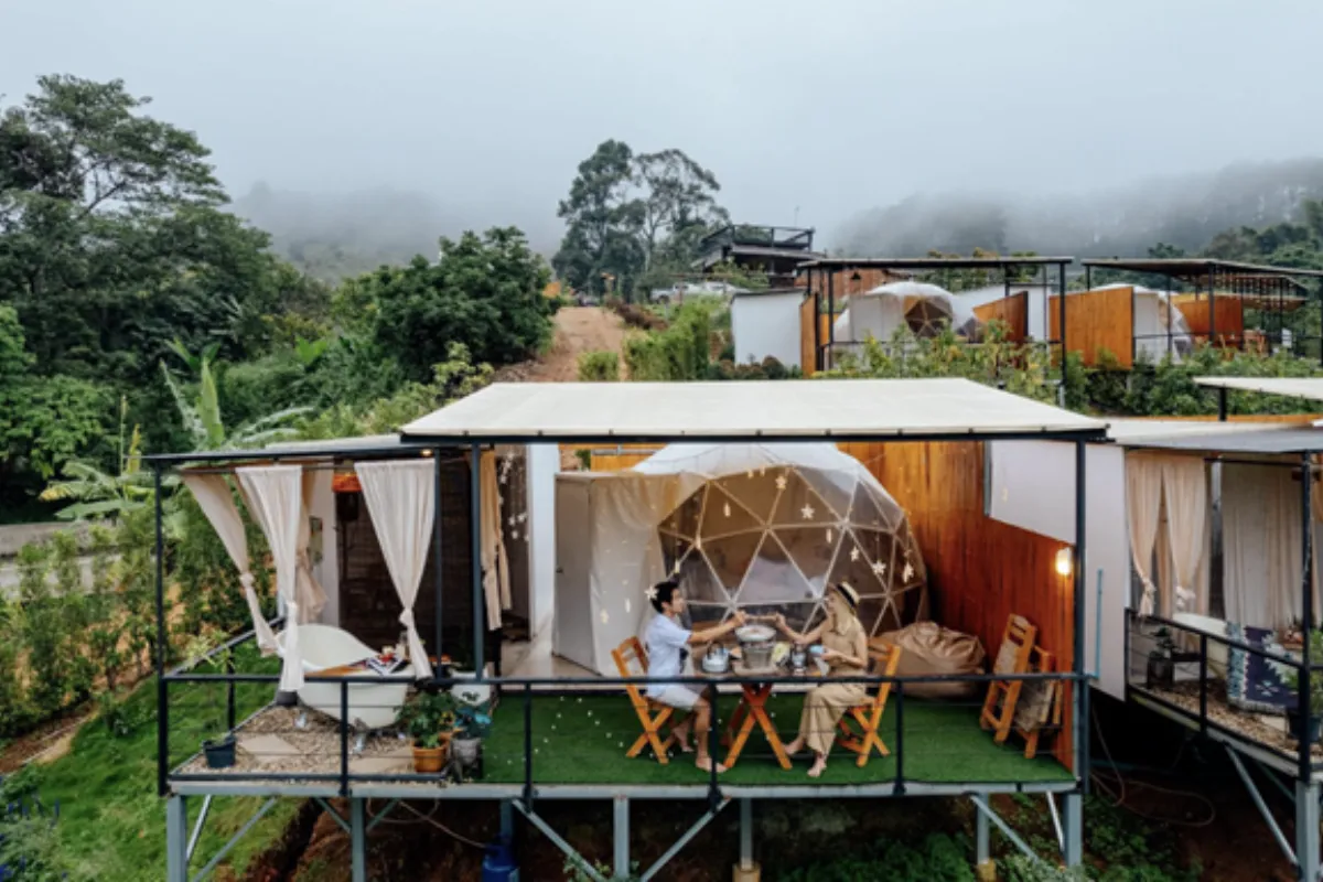 A couple is dining on the patio of their dome tent at Phu Morinn Cafe & Camping in Chiang Mai